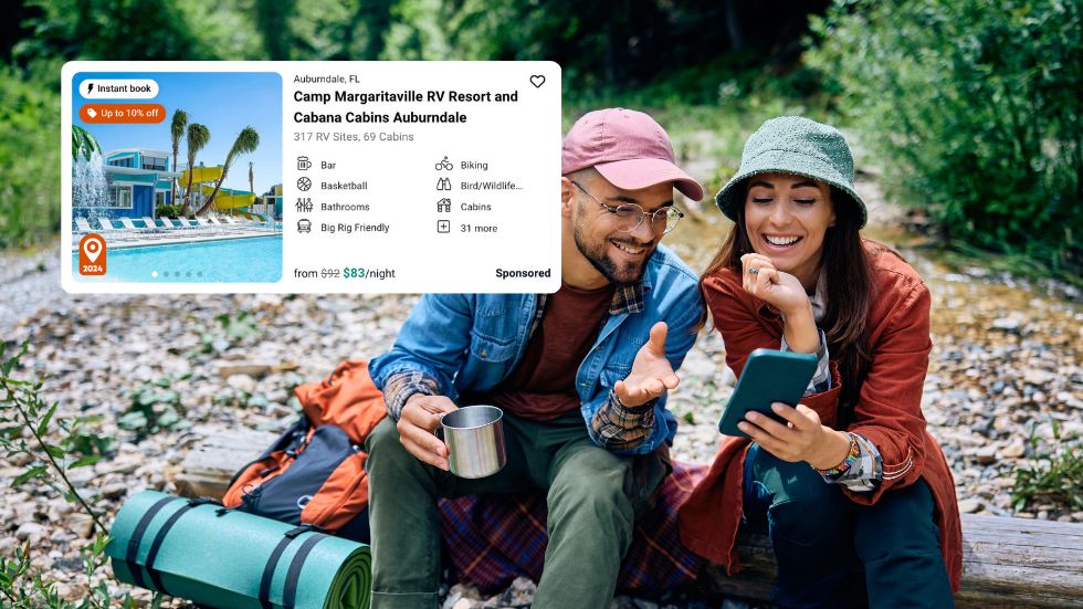 Two campers exploring Spot2Nite rate parity listing campgrounds on their phone while relaxing next to a river.